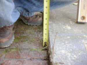 Photo of sinking foundation with tape measure showing distance. 