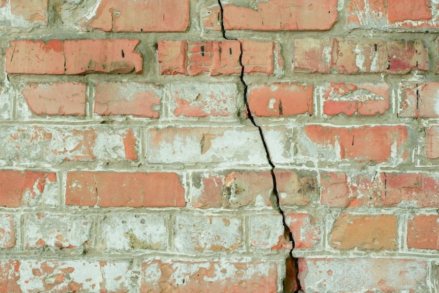 Old brick wall with a long, visible crack down the middle.