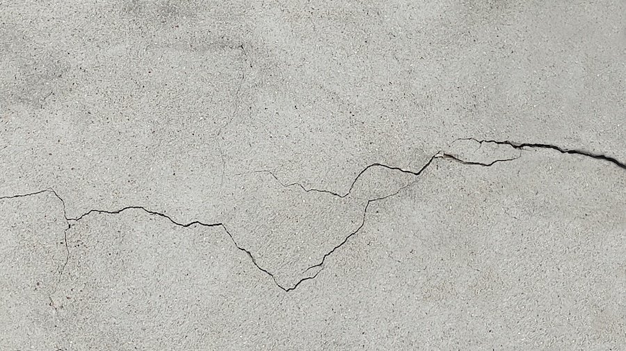 Cracked concrete surface covered with gray cement mortar.