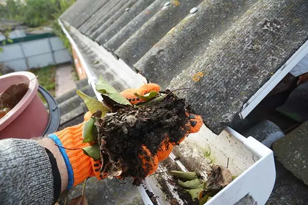 Rain Gutter Cleaning. Scooping leaves from gutter. Clean and Repair Rain Gutters and Downspout with roofer hands. Step by Step.