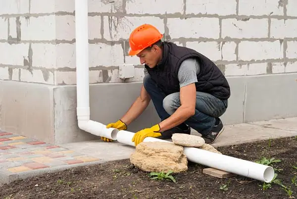 construction worker installs pipe the gutter system