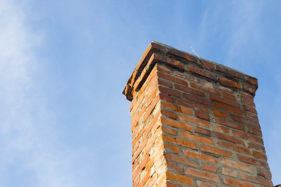 Old red brick chimney on blue clear sky 