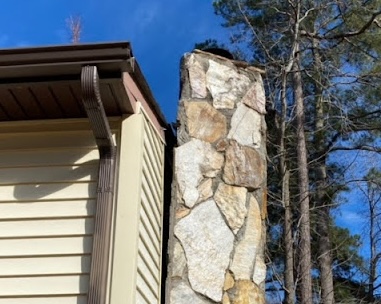 A stone chimney leaning away from a house