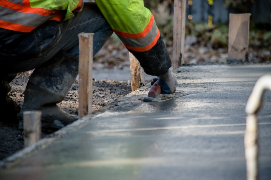 A construction worker smooths wet cement on a building foundation.