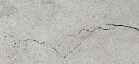 Cracked concrete surface covered with gray cement mortar.